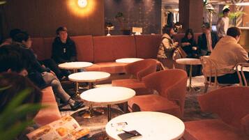 A dimly lit lounge area with round tables and cushioned seating.