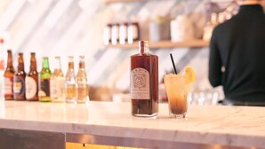 A bar counter with a variety of bottles and a drink with a lemon slice. - HOTEL SHE, KYOTO (Kyoto)