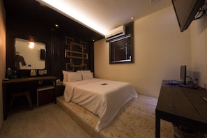 Une chambre avec un lit, un bureau, un miroir, un climatiseur et une fenêtre.
