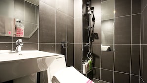 A modern bathroom with a white sink, a toilet, and a shower area. - Achasan Station Wall Hotel (Seoul)