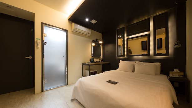 A hotel room with a bed, a nightstand, a mirror, and a door. - Achasan Station Wall Hotel (Seoul)