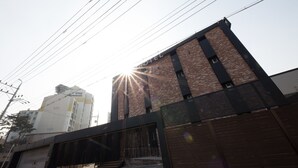A modern hotel with a brick facade, a gated entrance, and visible power lines. - Achasan Station Wall Hotel (Seoul)