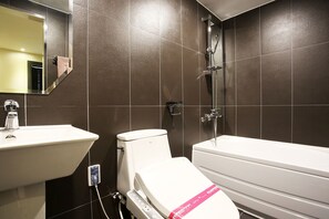 Une salle de bain avec un lavabo, des toilettes et une baignoire, le tout de couleur blanche.