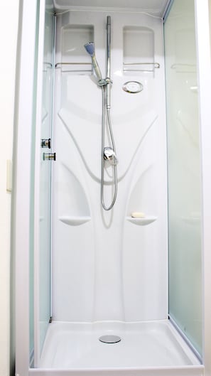 Une cabine de douche moderne et fermée, dotée d’un pommeau de douche à main, d’un porte-savon intégré et d’un panneau de commande pour régler la température et le débit de l’eau.