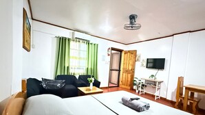 Une chambre d’hôtel comprenant un lit, un canapé, une petite table, une télévision et une porte donnant sur une autre pièce.