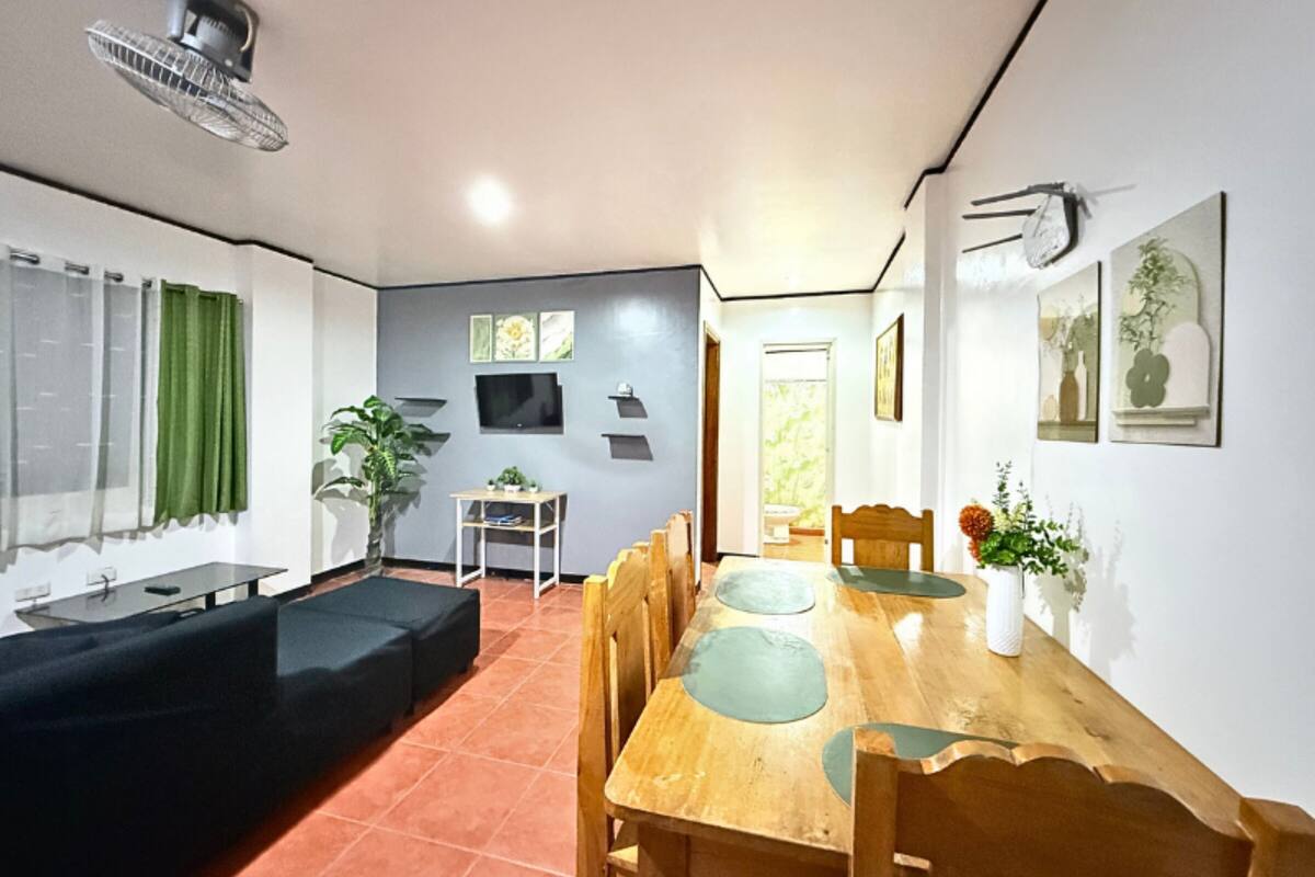Un espace de vie compact comprenant un coin repas, un coin salon et un tél éviseur fixé au mur.