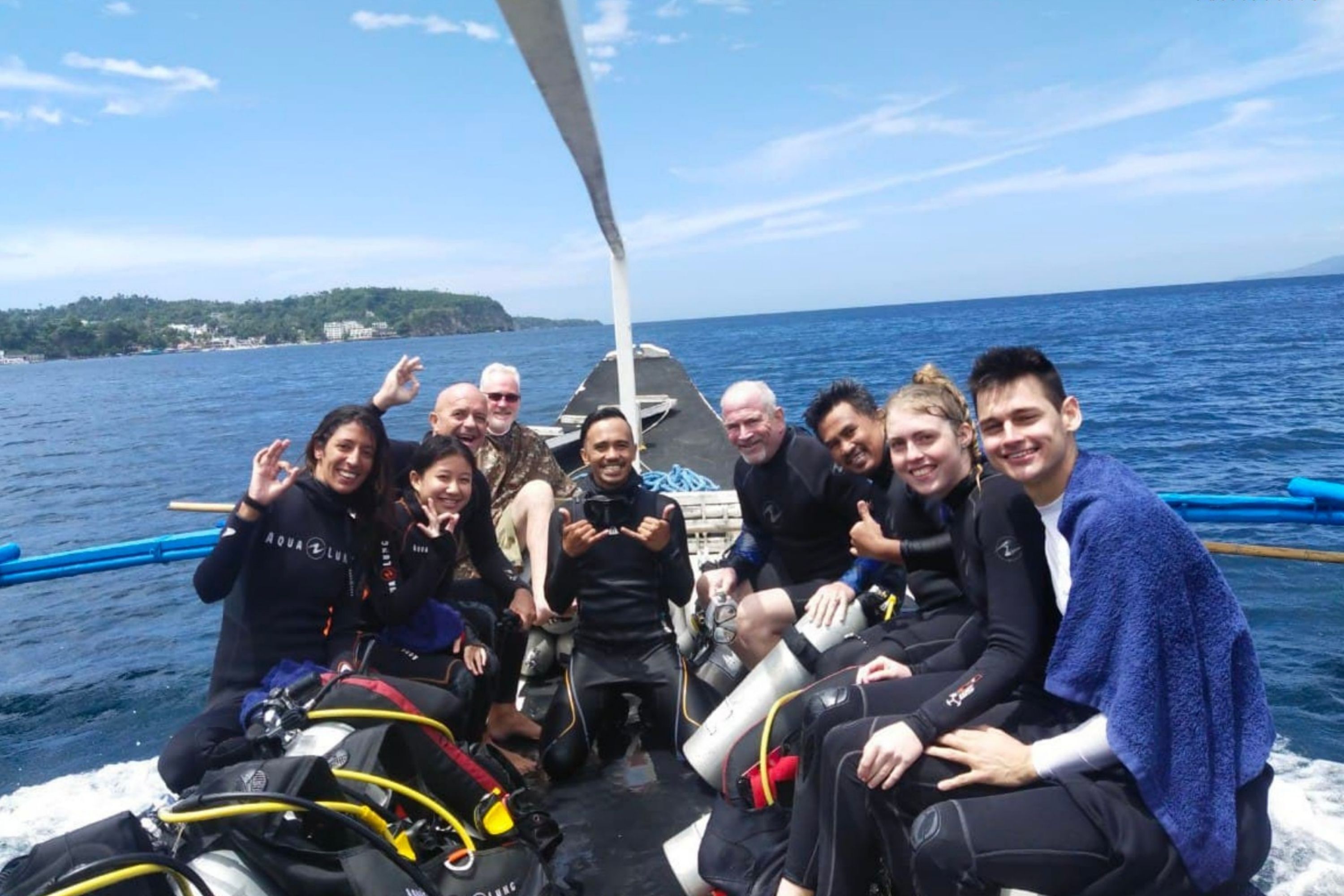 A group of people on a boat with scuba diving equipment, indicating a possible tour or recreational activity.