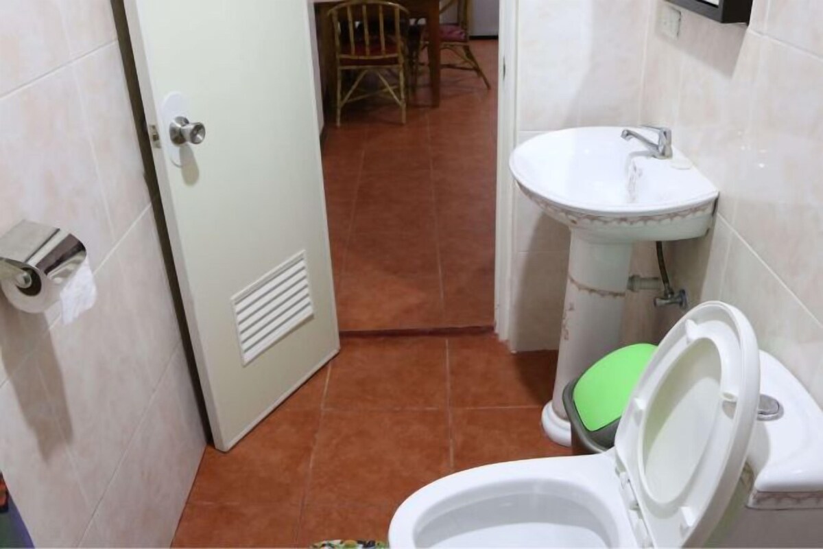 A bathroom with a toilet, sink, and a door leading to another room.