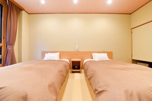 A hotel room with two beds, a nightstand, a headboard, and a window with curtains. - Shirahone Onsen Tsuruya Ryokan (Matsumoto)