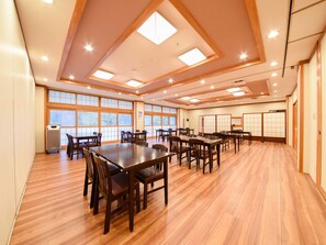 A spacious room with wooden flooring, multiple tables and chairs, large windows, and traditional sliding doors. - Shirahone Onsen Tsuruya Ryokan (Matsumoto)
