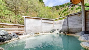 Un balneario de madera con una piscina cristalina rodeada de rocas.