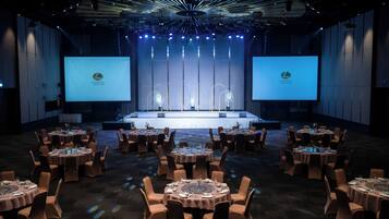 A conference room with a stage, multiple tables, and chairs arranged for a meeting.