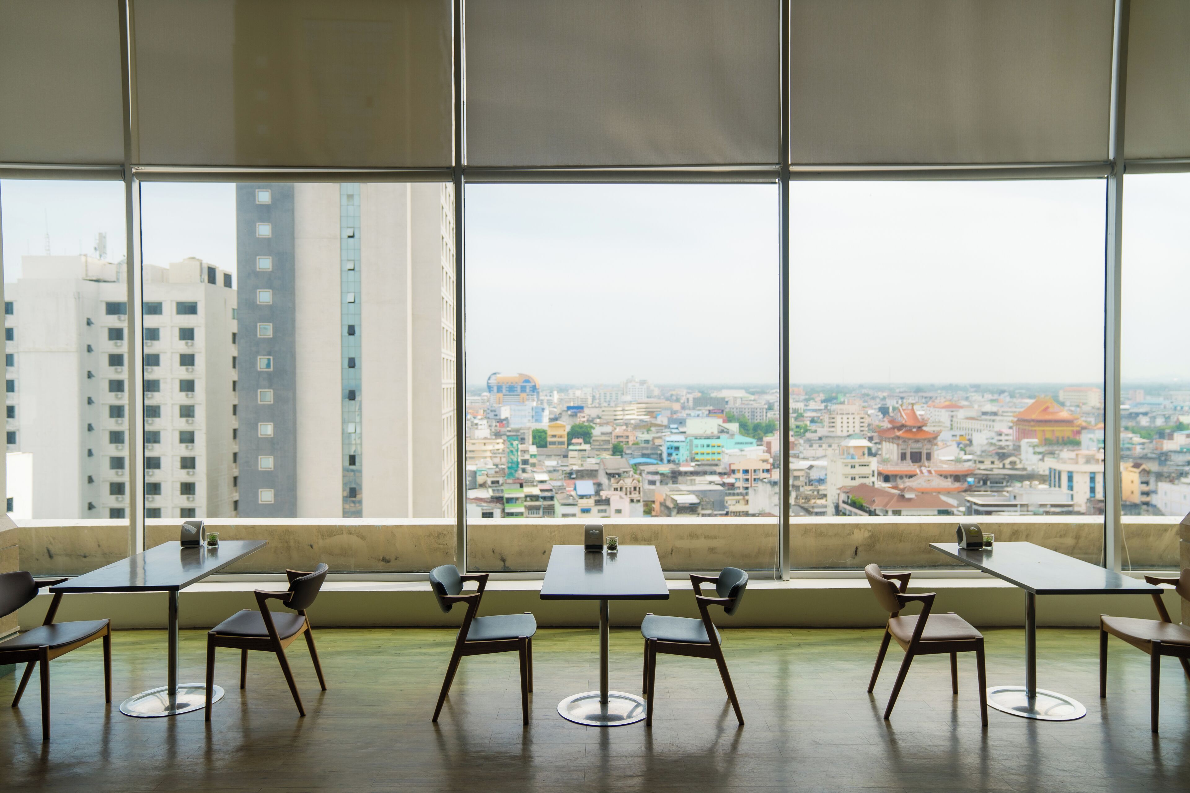 A conference room with a city view through large windows, featuring a table and chairs arranged for meetings.