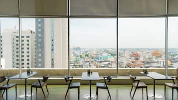 A conference room with a city view through large windows, featuring a table and chairs arranged for meetings.