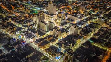 A nighttime aerial view of a densely built urban area with high-rise buildings and illuminated streets.