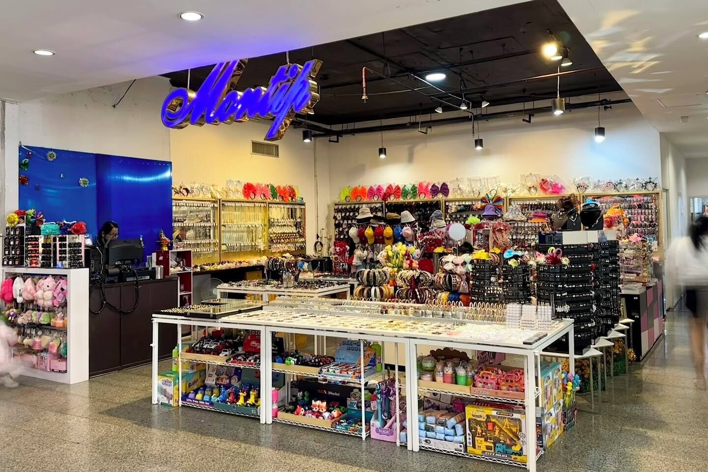 Una tienda luminosa con un letrero de neón, estantes llenos de juguetes y una variedad de artículos coloridos.