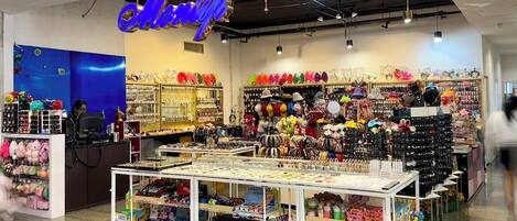 Una tienda luminosa con un letrero de neón, estantes llenos de juguetes y una variedad de artículos coloridos.