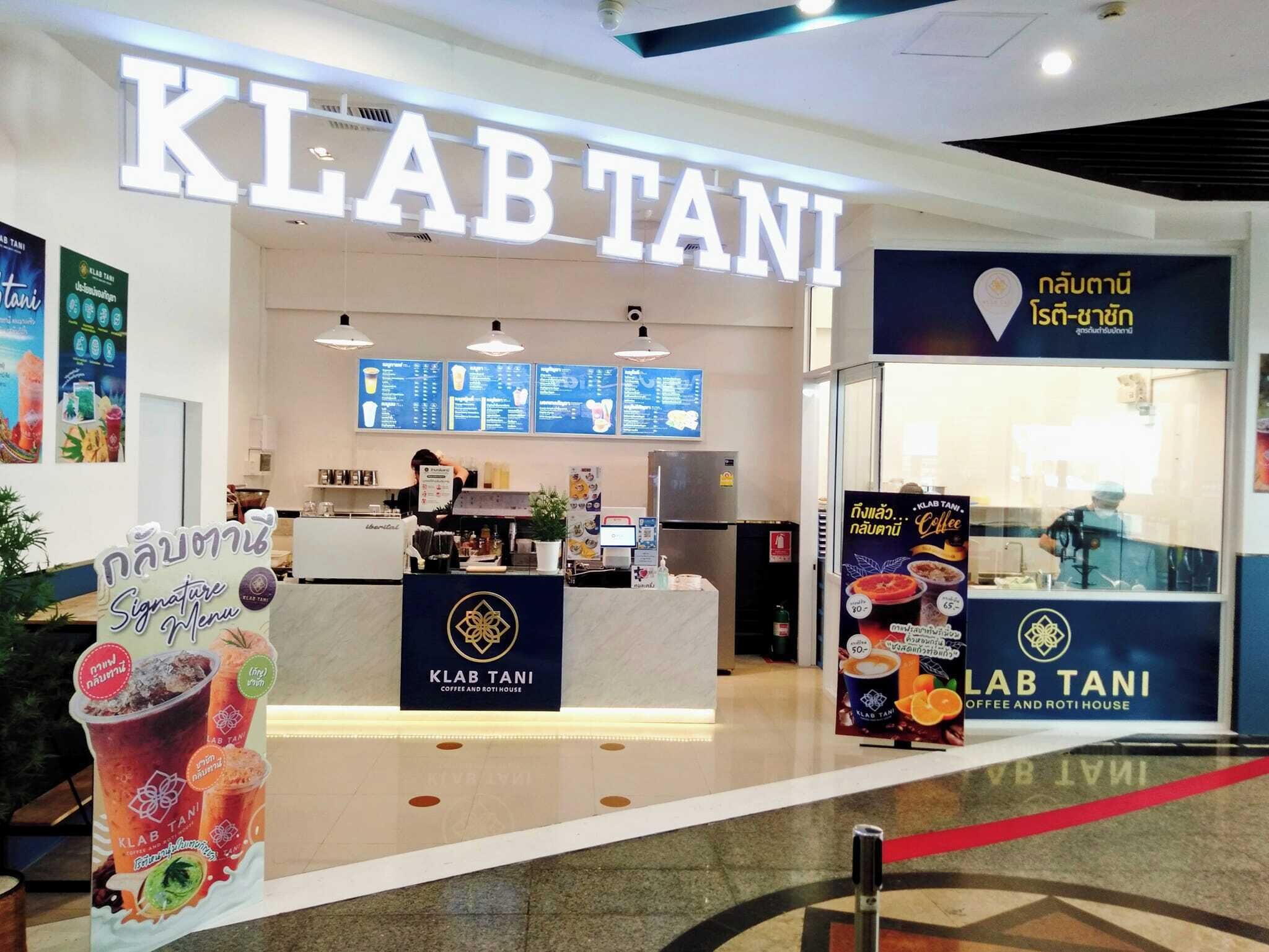 A coffee shop named KLAB TANI with a visible counter, menu boards, and a signboard advertising signature menu items.