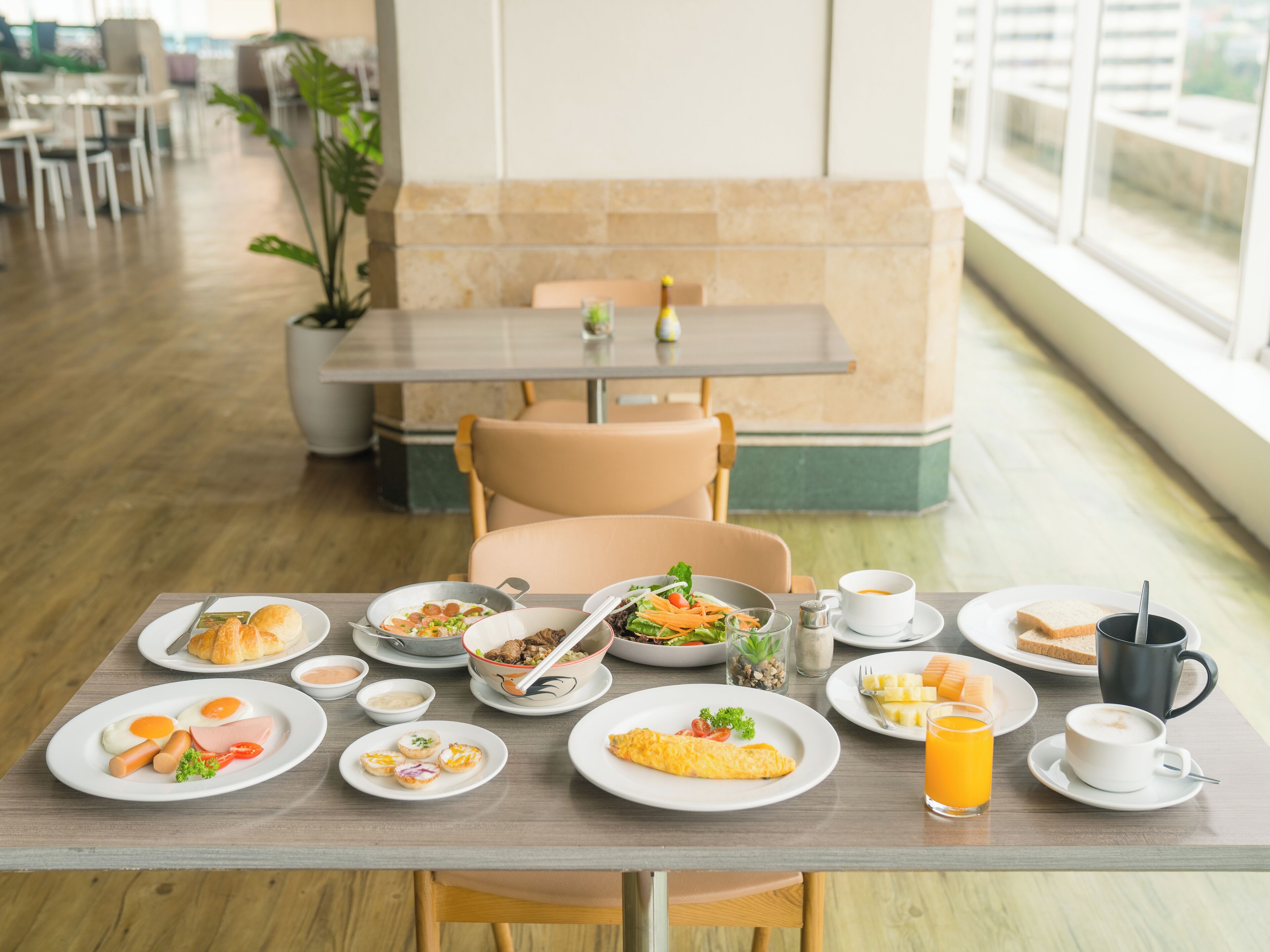 A dining table with various breakfast items, including eggs, sandwiches, and a cup of coffee.