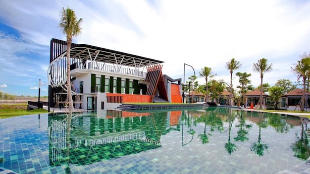 A modern hotel with a pool, palm trees, and a unique architectural design. - Cha-am Eco Camp (Cha-am)