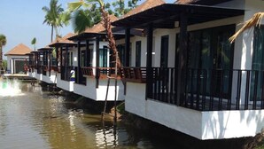 A row of floating houses with thatched roofs, connected by walkways over water. - Cha-am Eco Camp (Cha-am)