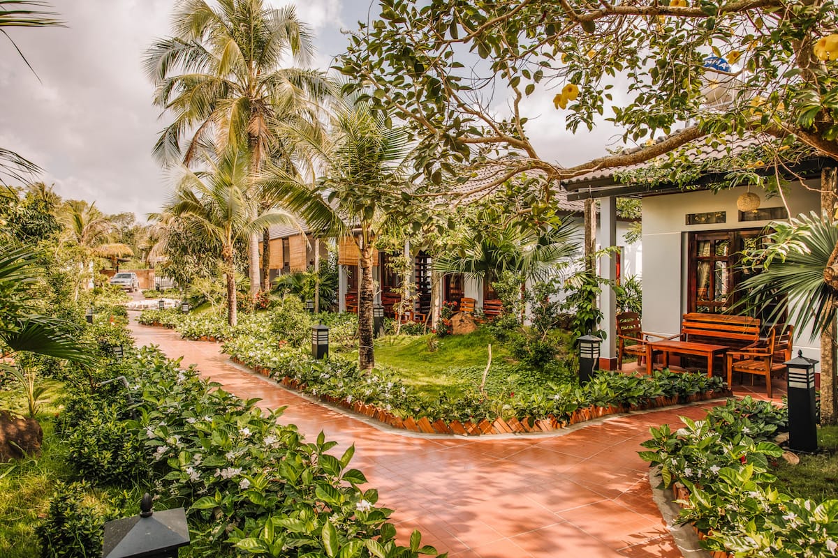 A garden pathway leading to a building with a covered seating area.