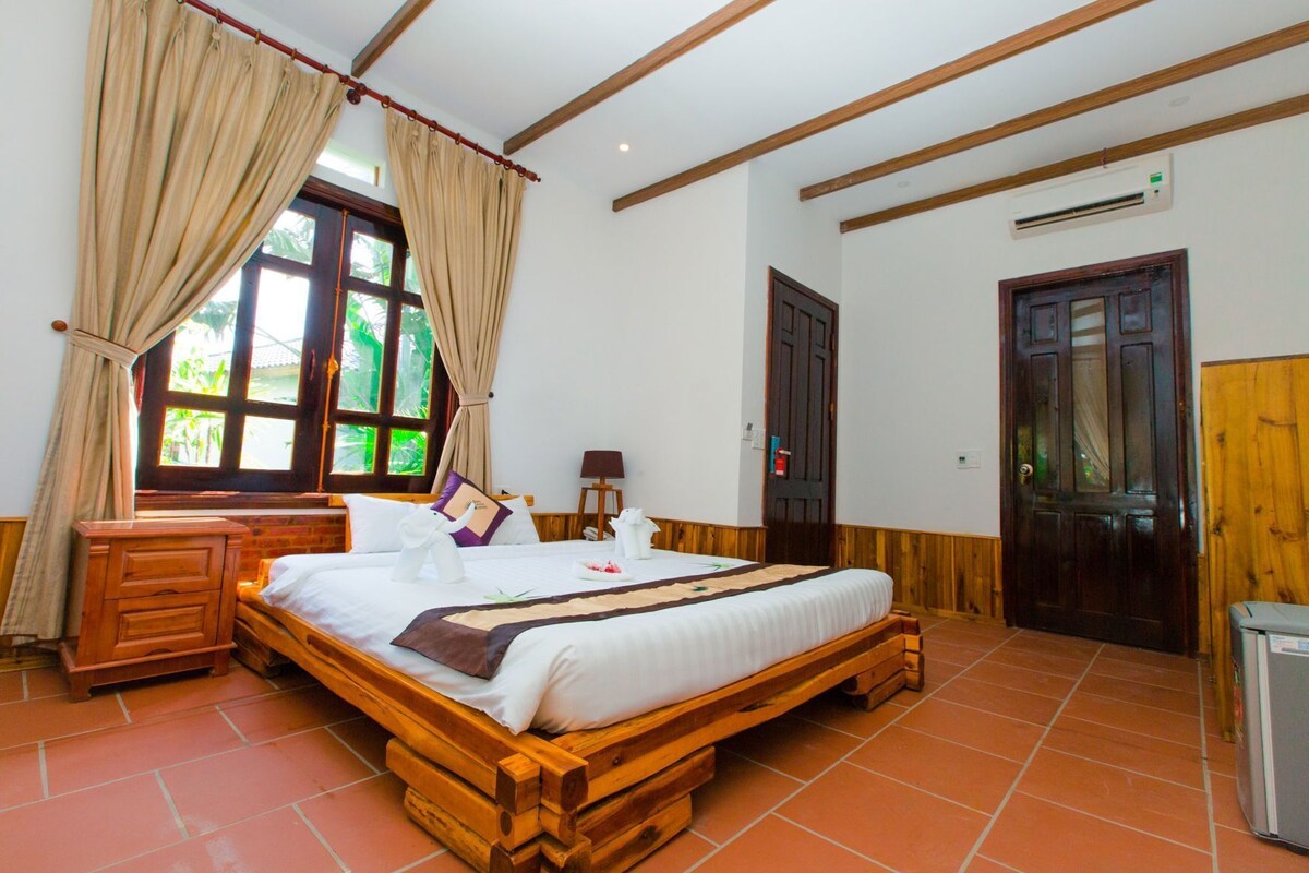 Una cama de madera en una habitación con ventana, un aparador de madera y una puerta.