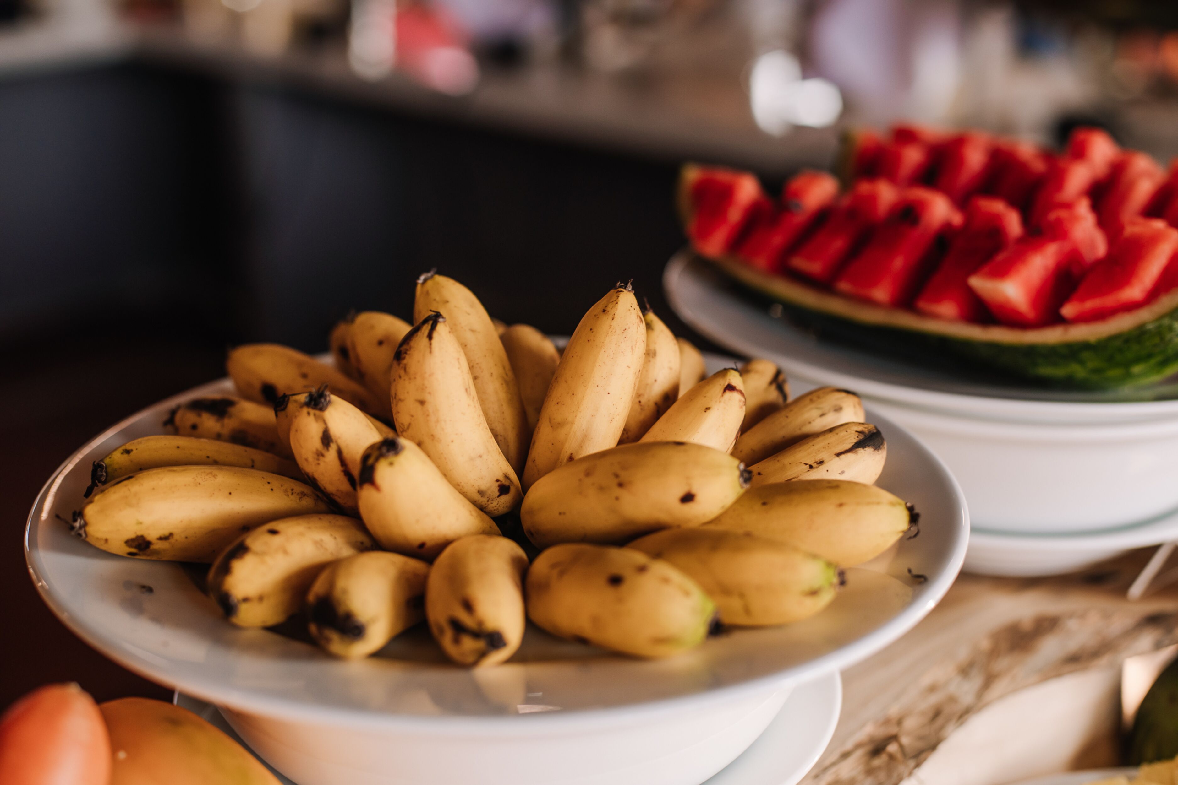 A plate of bananas and a plate of watermelon slices.