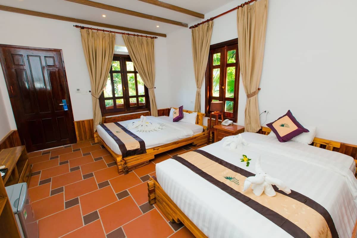 A room with two beds, a wooden door, and a tiled floor.