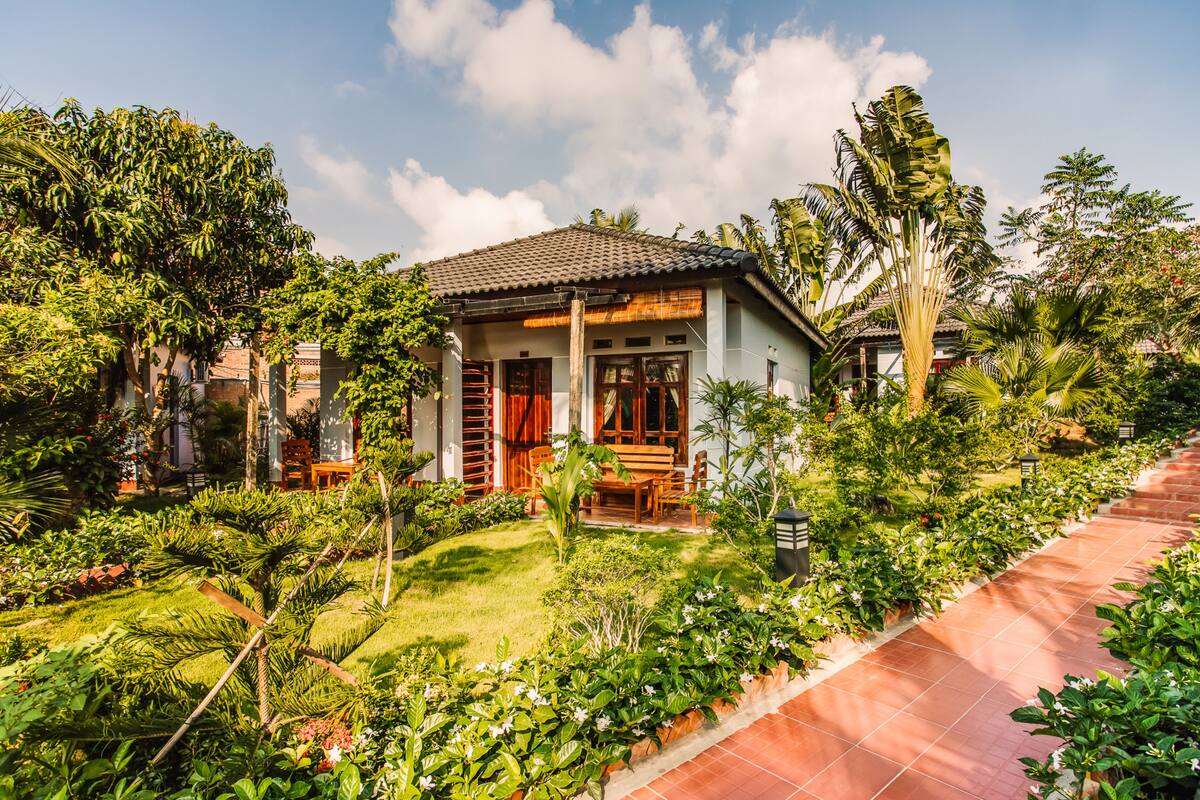 A house with a tiled roof, surrounded by lush greenery and a garden.