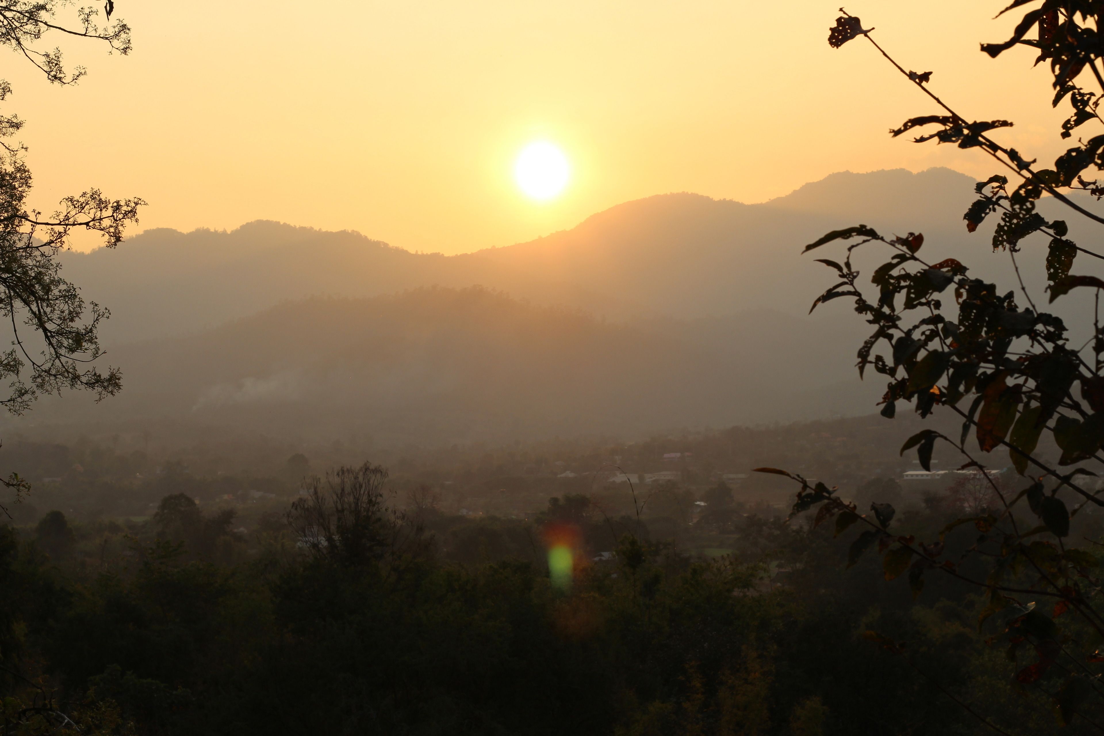 Un atardecer sobre un paisaje montañoso con vista a un pueblo abajo.