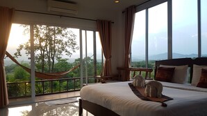 Un dormitorio con una cama grande, vistas a zonas verdes y montañas, y una hamaca.