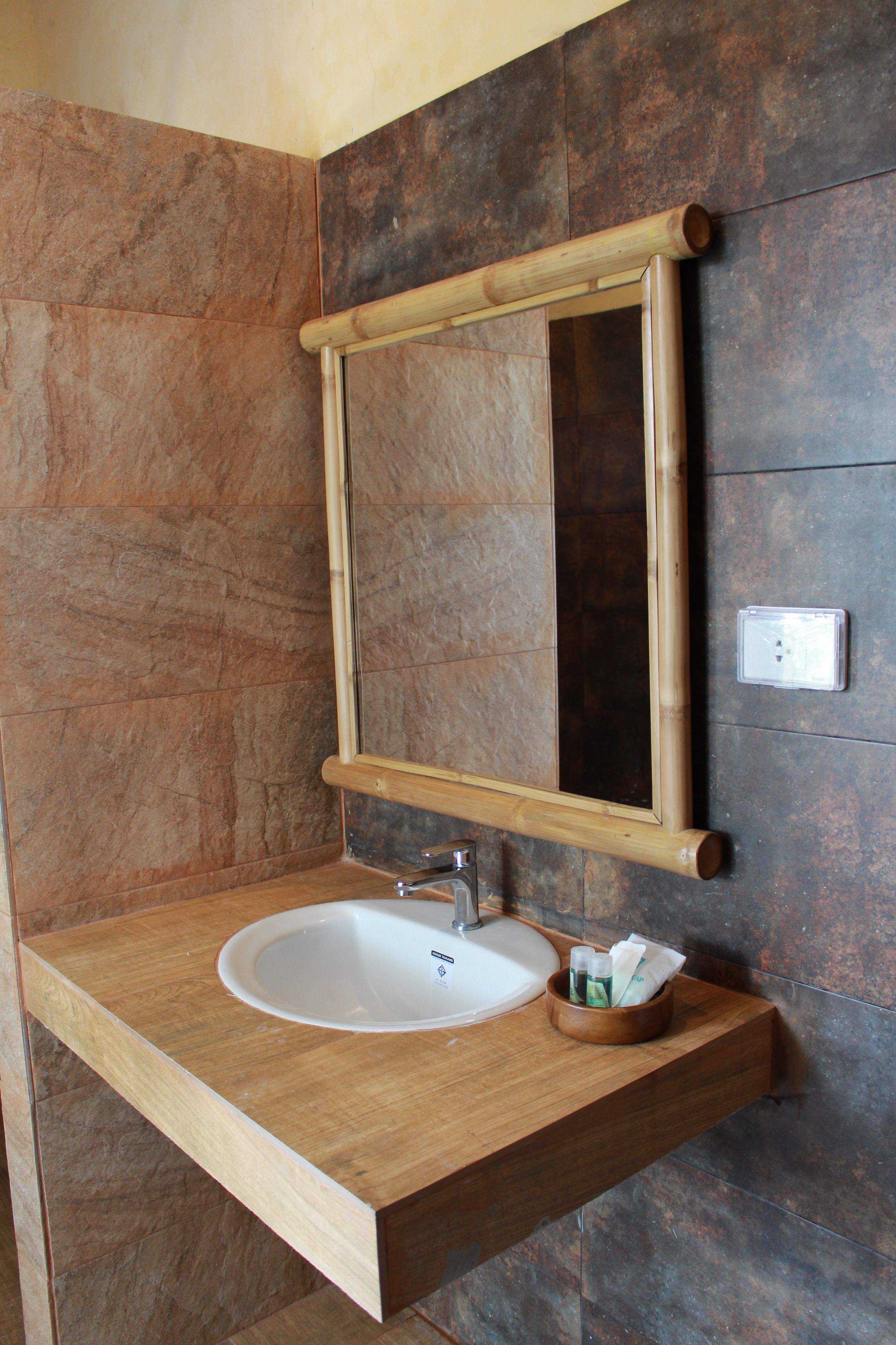 Een badkamer met een houten wastafelmeubel, een witte wasbak en een spiegel met houten lijst.