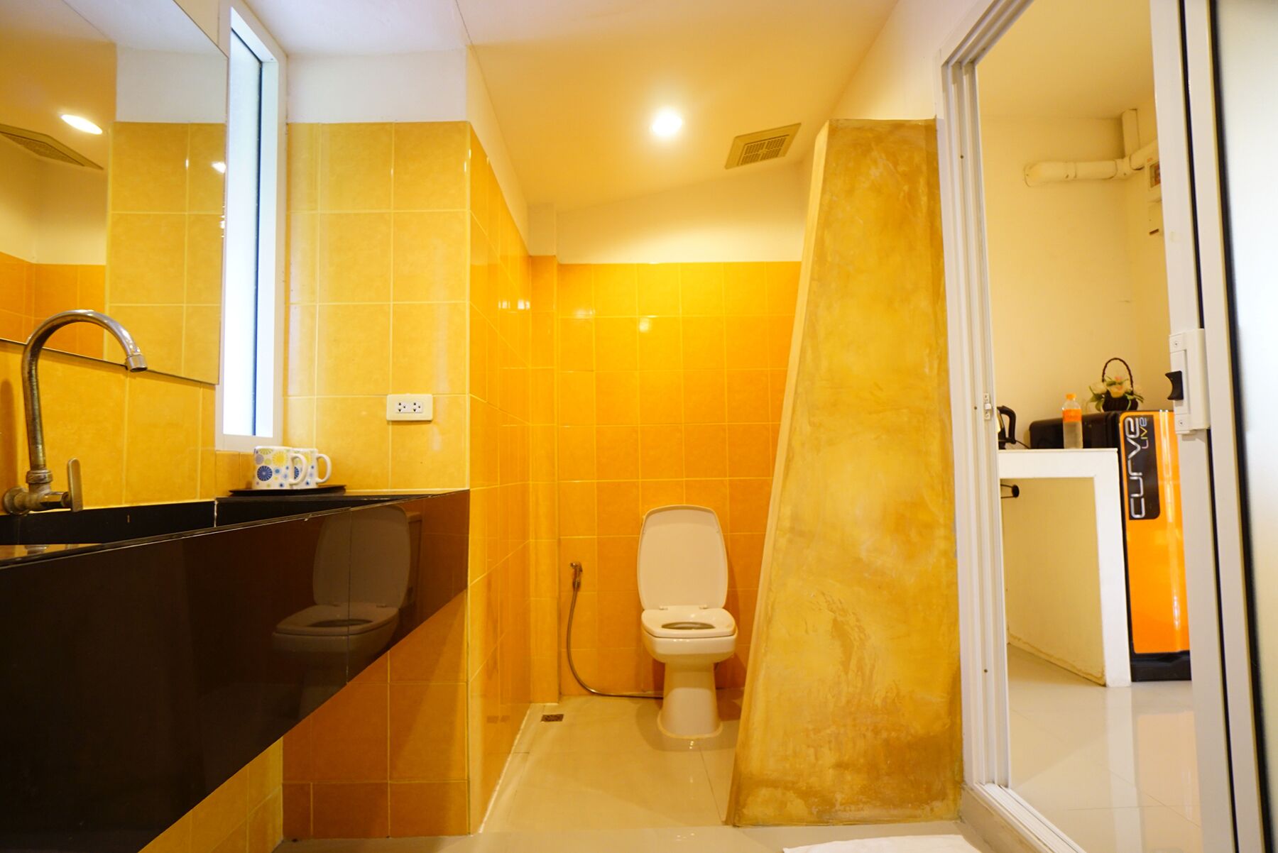 A modern bathroom with yellow tiles, a black sink, a white toilet, and a shower area.