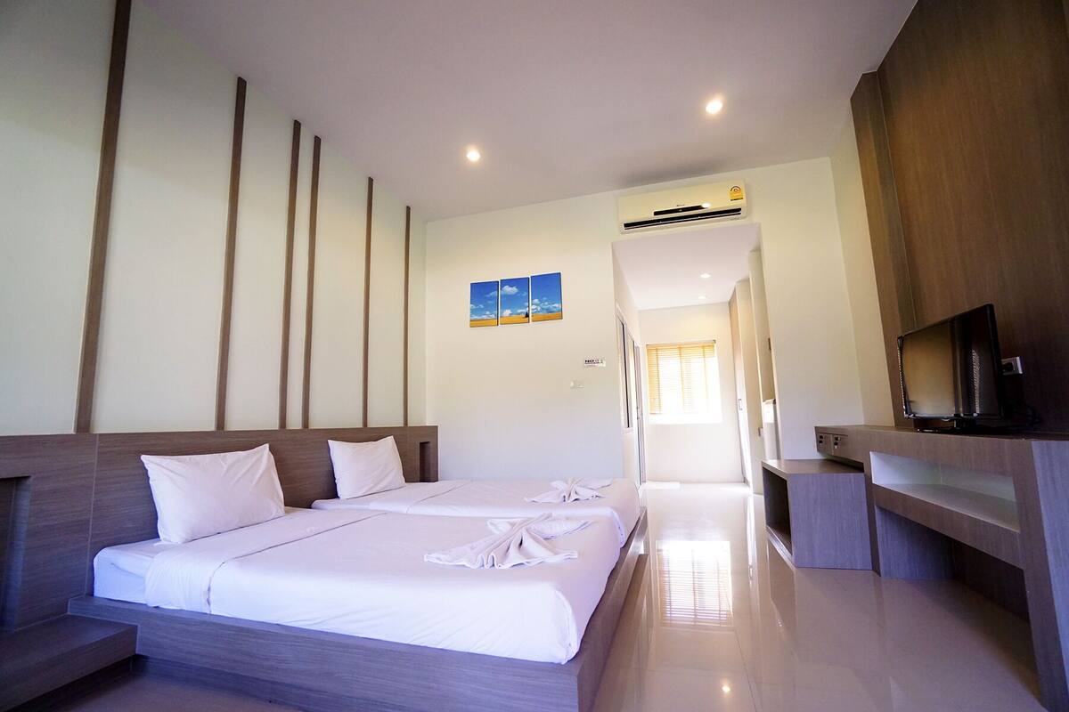 Een hotelkamer met een groot bed, een televisie en een airconditioning.