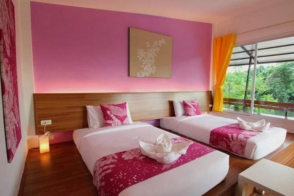 Een hotelkamer met twee bedden, roze wanden, een houten hoofdbord en een raam met uitzicht op groen.