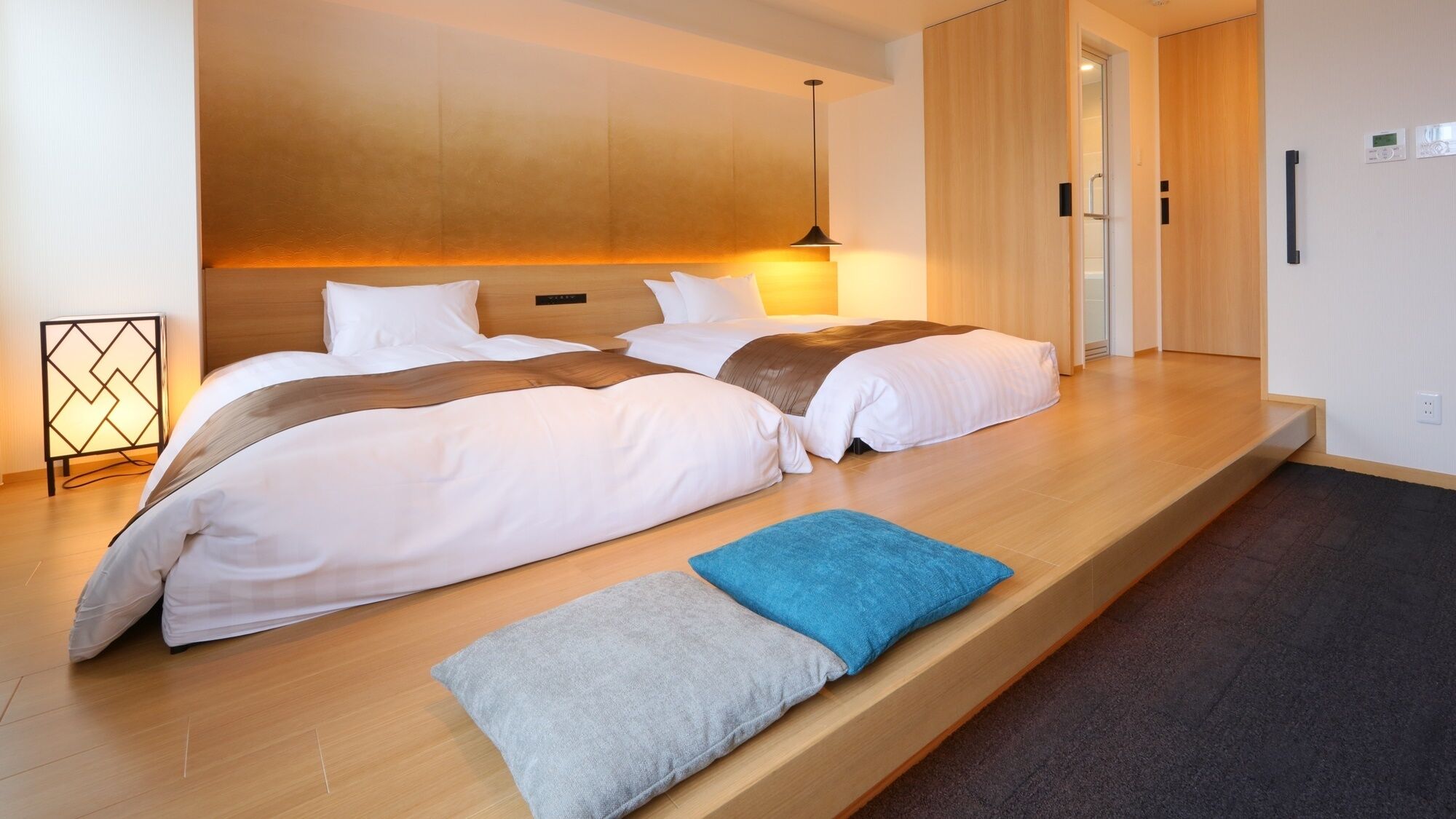 A modern hotel room with a large bed, a bedside table, and a built-in bench.