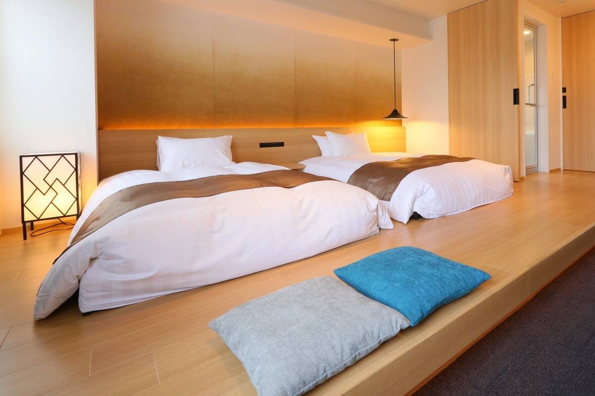 A modern hotel room with a large bed, a bedside table, and a built-in bench.