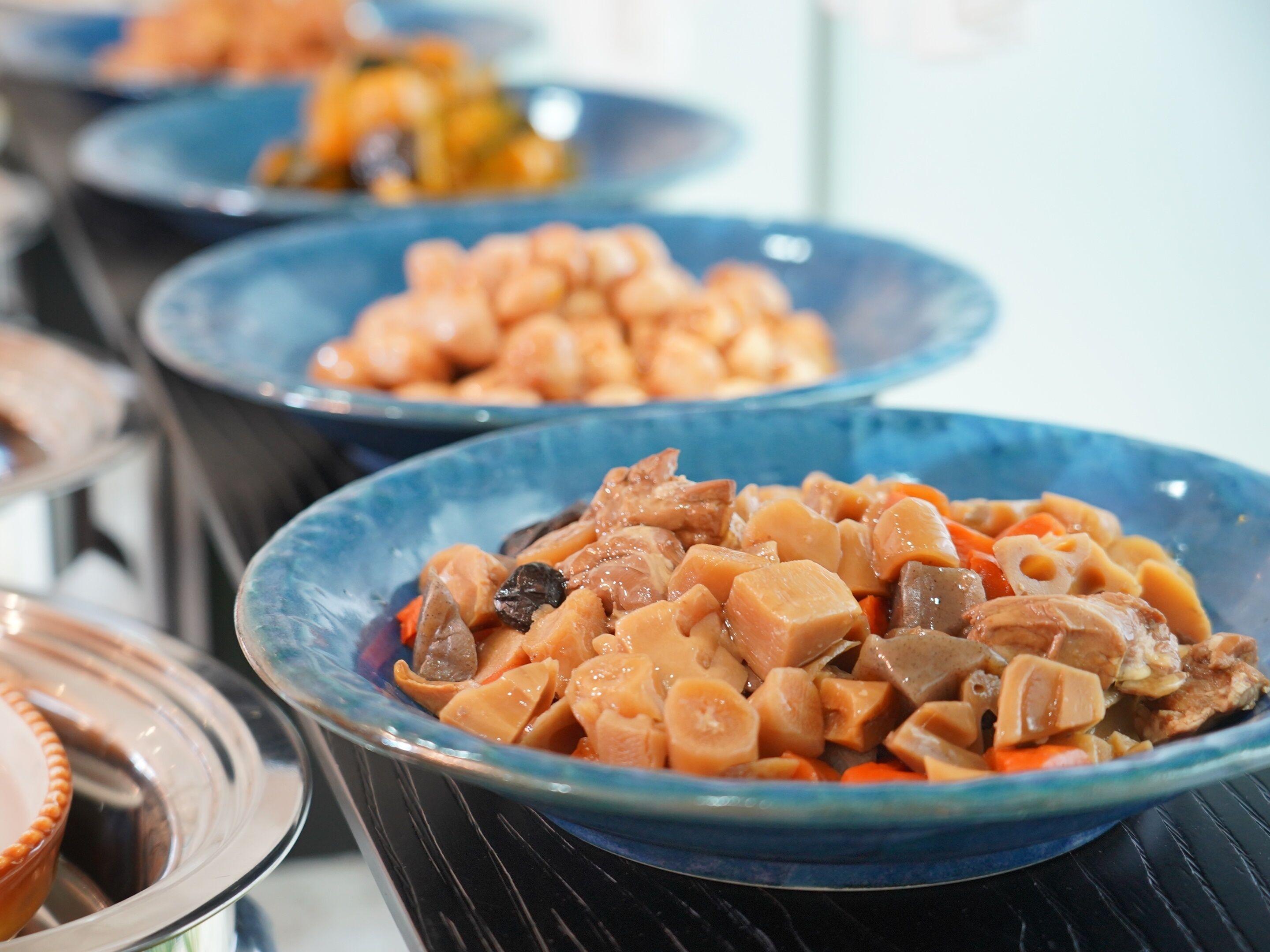 A buffet with various dishes, including a prominent bowl of what appears to be a meat and vegetable stew.