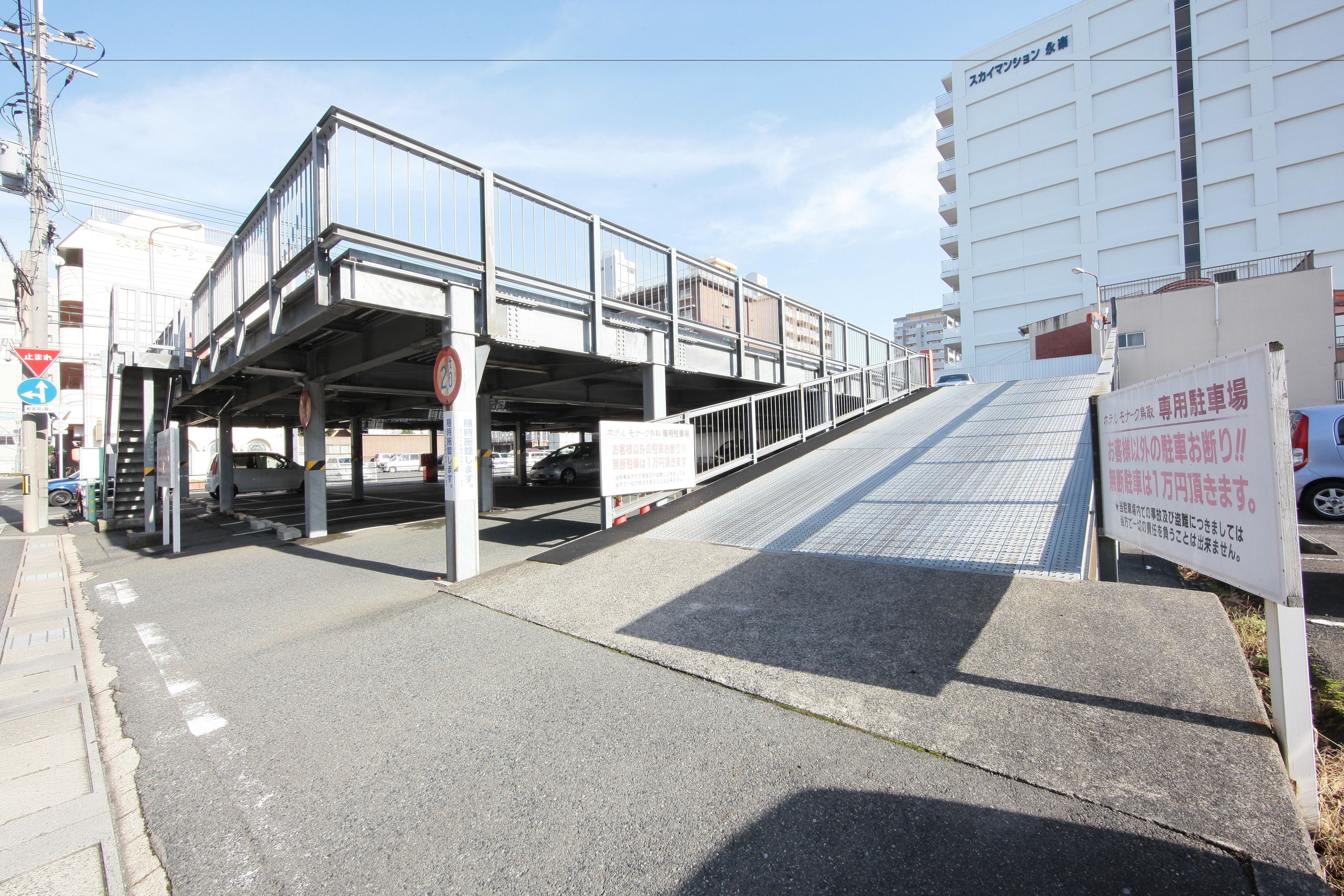 A pedestrian bridge with a signboard and a building in the background.