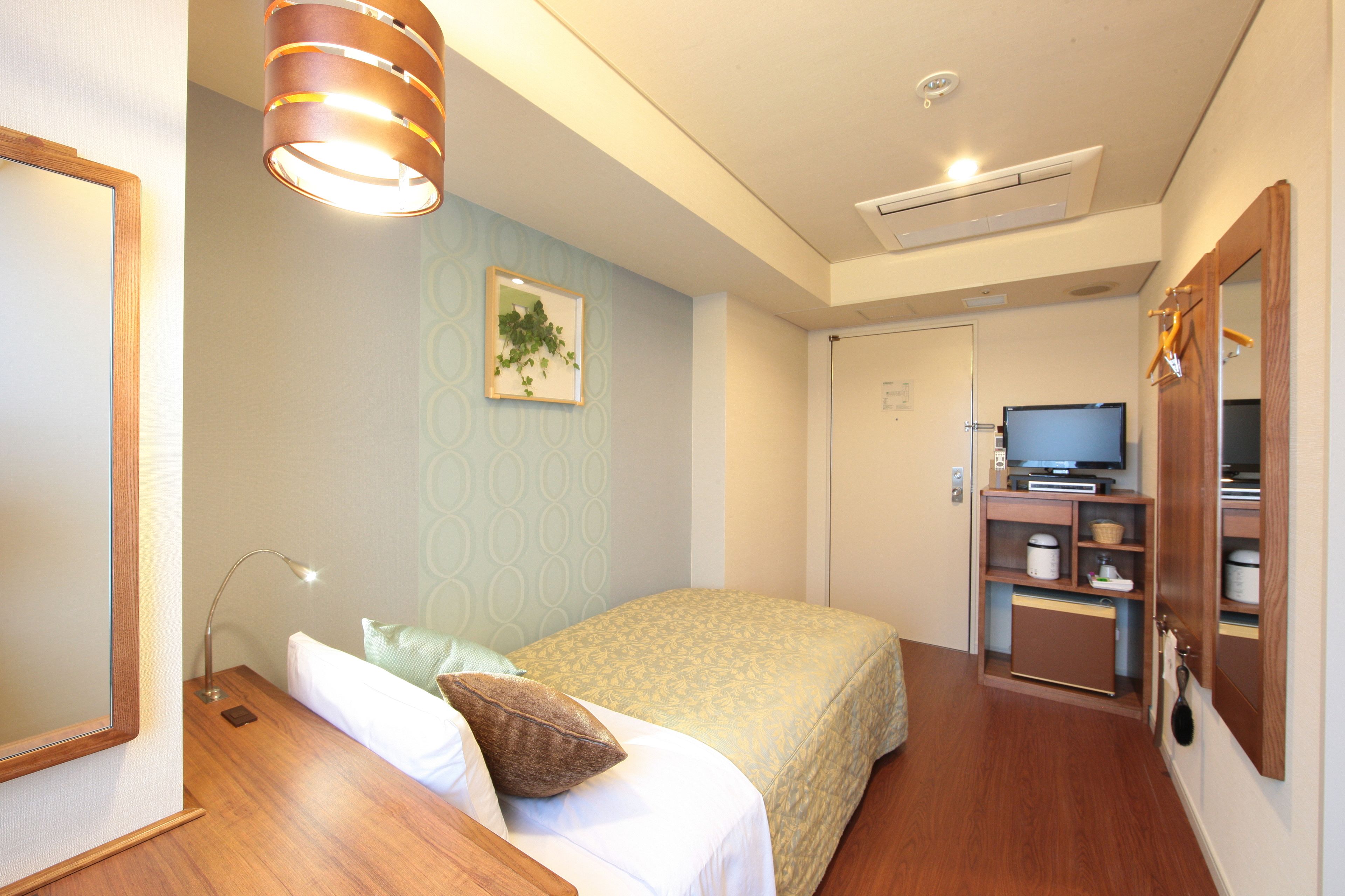 Ein Hotelzimmer mit Bett, Nachttischlampe und einem Fernseher in der Ecke.