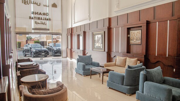 Un hall espacioso con diseño moderno, que ofrece una variedad de opciones de asientos como sofás y sillones, y una amplia entrada con puertas de vidrio.