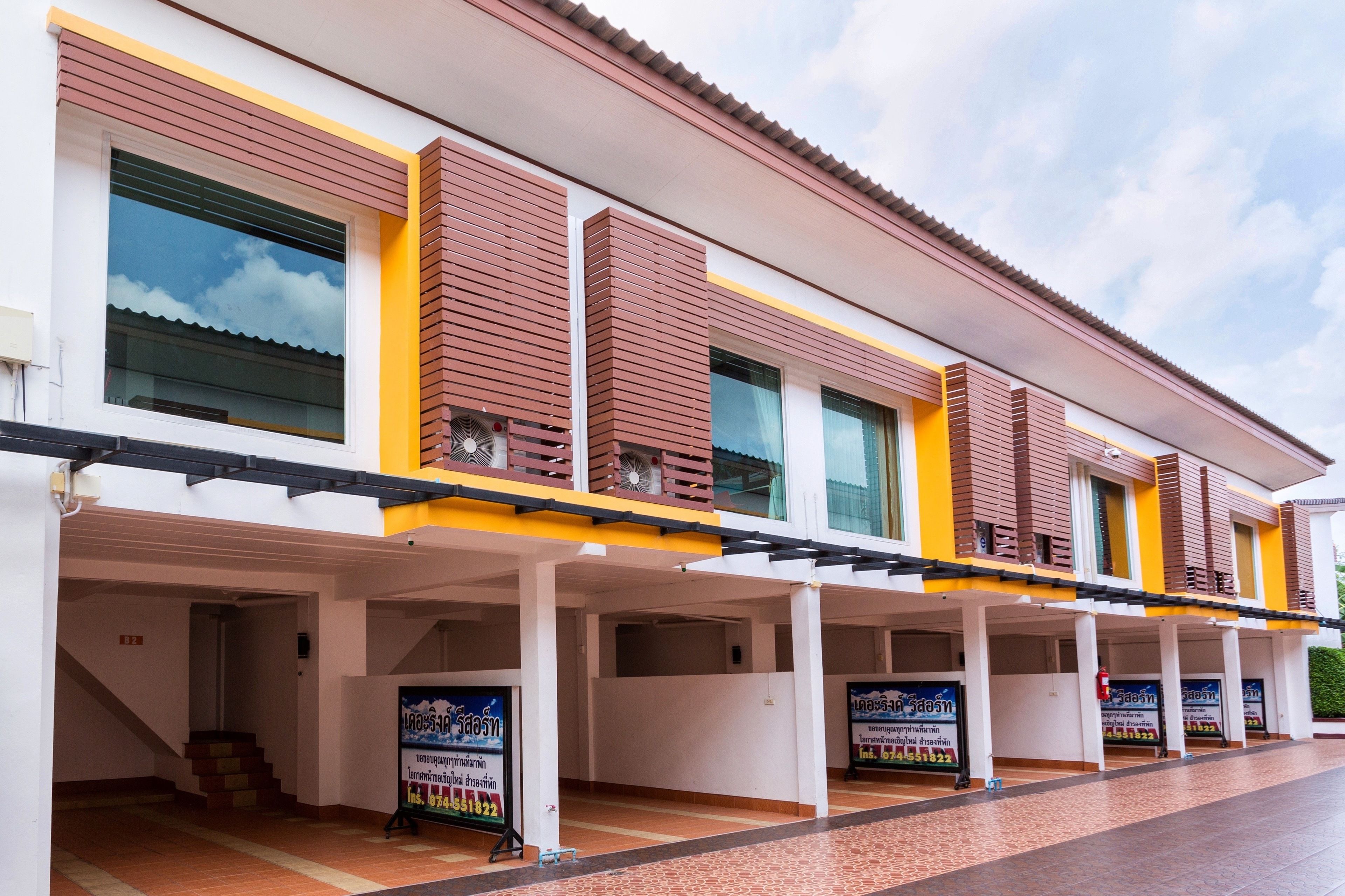 A hotel with a covered outdoor area, multiple windows, and a staircase leading to an entrance.