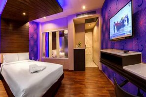 Ein modernes Hotelzimmer mit Bett, Fernseher und Schreibtisch.
