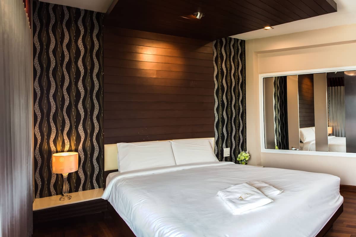 Ein modernes Hotelzimmer mit einem großen Bett, Holzpaneelen und einem großen Fenster.