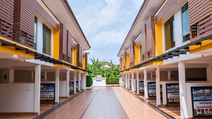 A corridor with rows of rooms, each with a window and a door. - The Ring Hotel (Hat Yai)