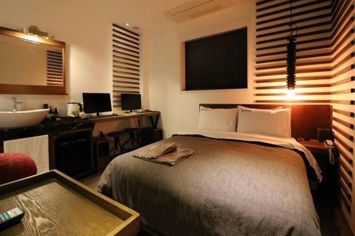 Une chambre d’hôtel avec un lit, une table de chevet, un bureau et une grande fenêtre.