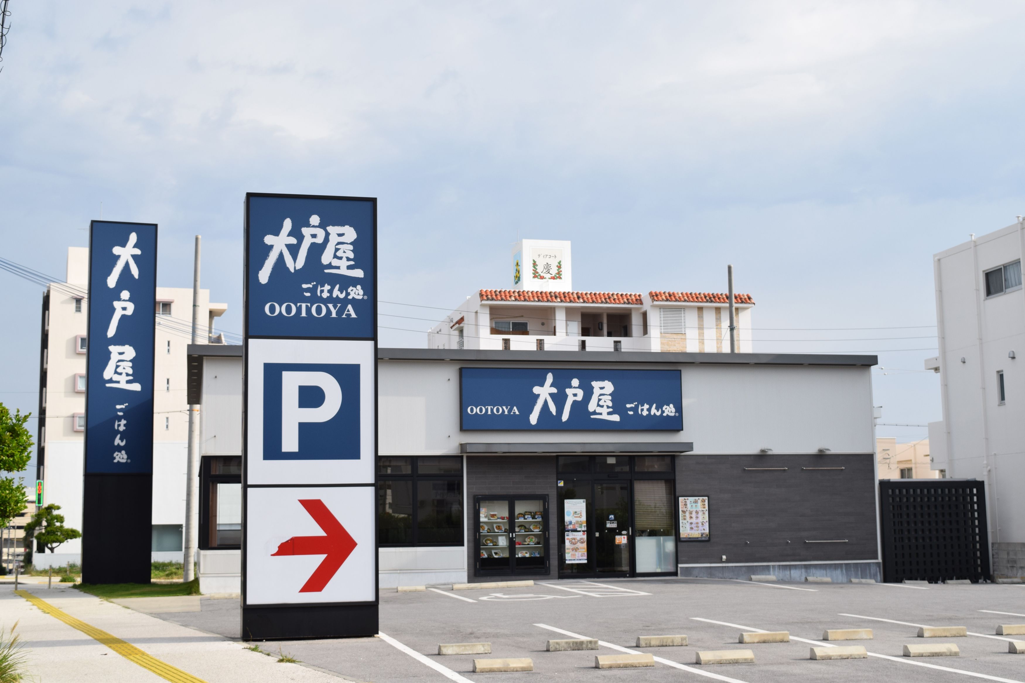 A building with a sign for OOToya and a parking sign with an arrow.