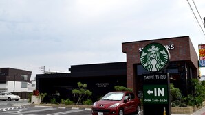 A Starbucks drive-thru with a red car parked in the lot. - Rainbow Terrace (Ginowan)