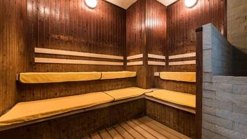 Una sauna con paredes y bancos de madera, una pared de piedra en un lateral y un techo con patrón de cuadrícula.